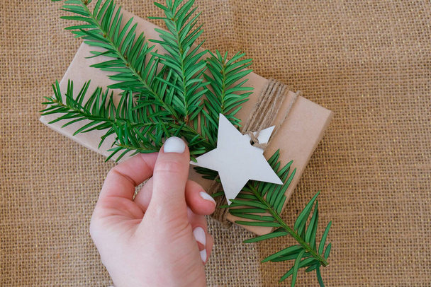 Schachtel mit Neujahrsgeschenken, eingewickelt in Bastelpapier und dekoriert mit Tannenzweig. Feiertage und Geschenke Konzept. Handgemachte umweltfreundliche alternative grüne Weihnachtsgeschenke ohne Abfall Nachhaltiger Lebensstil - Foto, Bild
