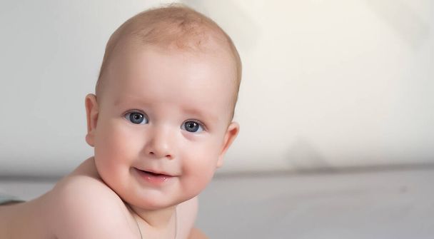 Bebê sorridente bonito em um sofá cinza. - Foto, Imagem