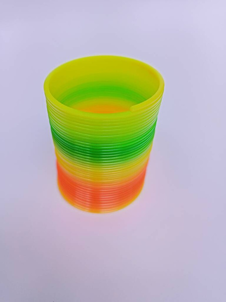 Rainbow plastic coil spring toy on white background, children's creative education - Foto, imagen