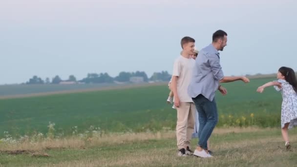 Fun of a happy family. Family walk outdoors in the field, on green grass. Mom, dad and children are walking on a warm summer day. - Záběry, video