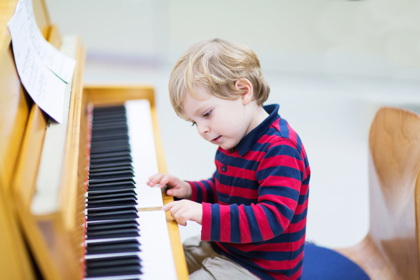 Дворічний хлопчик грає на фортепіано, музичний вчений
. - Фото, зображення