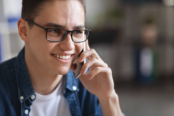 Close Up Portrait Of Millennial Handsome Man Wearing Eyeglasses Talking On Mobile Phone Indoors, Young Cheerful Guy Having Pleasant Conversation, Stylish Male Looking Away And Smiling, Copy Space - Fotografie, Obrázek