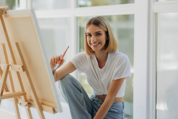 Beautiful artist in her studio. Happy girl likes to draw. - Foto, afbeelding