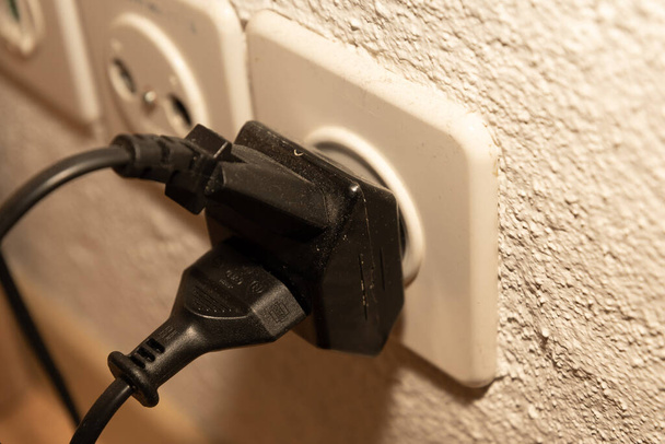 Vaduz, Liechtenstein, September 6, 2022 Electric power plug put in a socket to generate electricity in an apartment - Photo, image