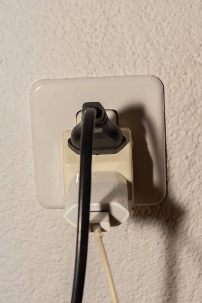 Vaduz, Liechtenstein, September 6, 2022 Electric power plug put in a socket to generate electricity in an apartment - Foto, Imagem