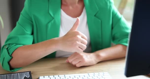 Businesswoman gesturing thumbs up in monitor screen at workplace. Remote recommendations for excellent work and likes for effective work - Кадры, видео