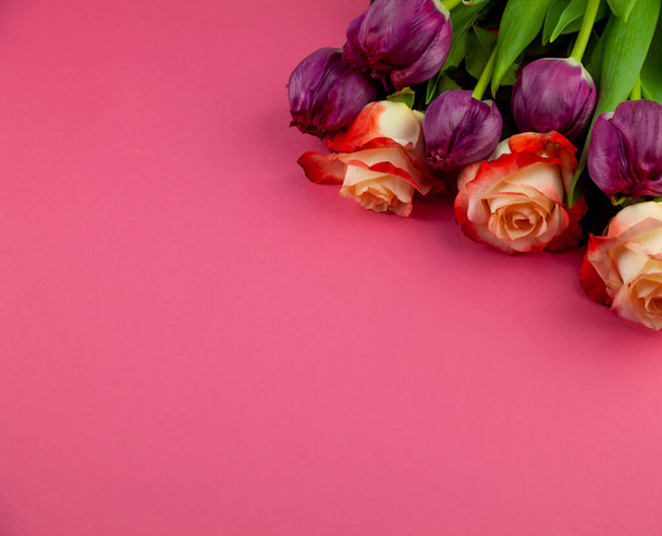 Bouquet of roses and tulips on a plain pink background. Layout for a greeting card. Spring concept. Copy space. Flowers top view. Tulip flower. - Photo, Image