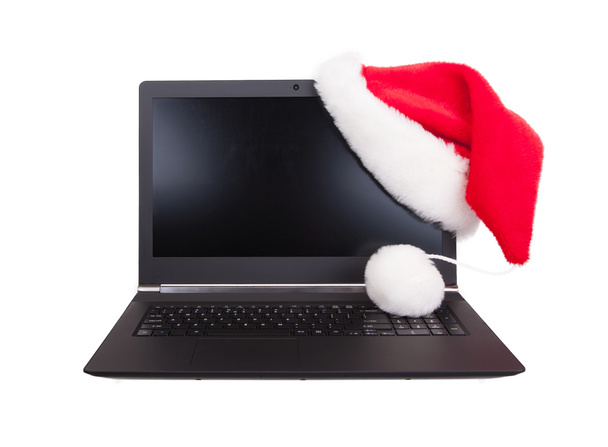 Moderne opengeklapte laptop met rode Kerstman hoed zetten op LCD-hoek - Foto, afbeelding