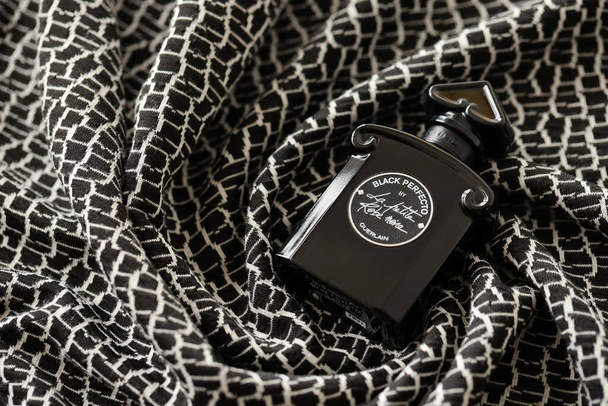 TERNOPIL, UKRAINE - SEPTEMBER 2, 2022 Black Perfecto La Petite Robe Noire by Guerlain perfume bottle on dark plaid in monochrome colors - Fotó, kép