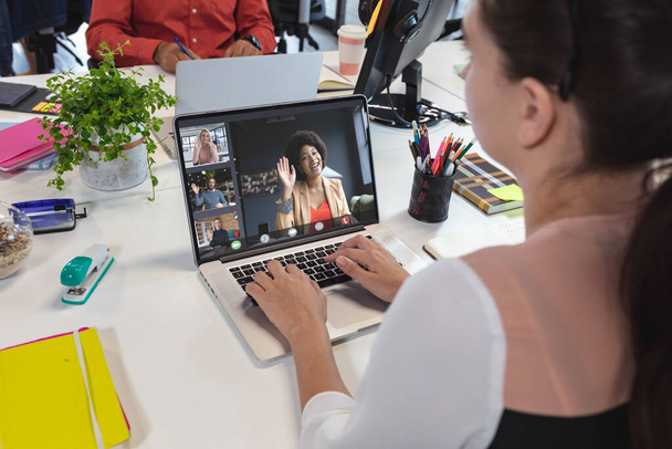 Caucasian businesswoman having video call with colleagues. Global business and digital interface concept, digital composite image. - Photo, image