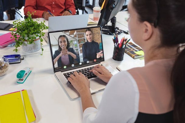 Caucasian businesswoman having video call with colleagues. Global business and digital interface concept, digital composite image. - Фото, зображення