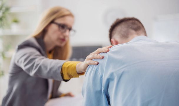 Defocused blond woman psychologist helps stressed patient man sitting in bright doctor office, health care concept - Фото, изображение