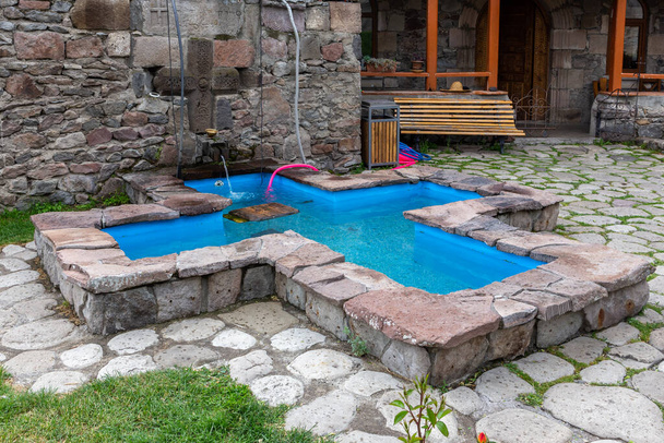 Cross-shaped stone pool with turquoise clear water in Zarzma Monastery of Transfiguration, medieval Orthodox Christian monastery located in the village of Zarzma, Georgia. - Photo, Image