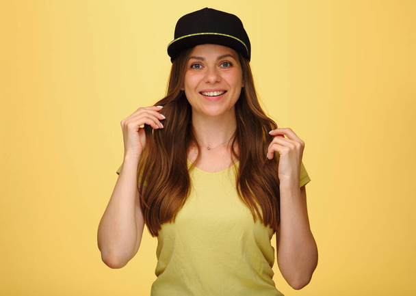 Smiling happy woman with straight hair in black cup isolated on yellow. - Foto, afbeelding