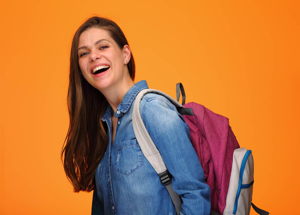 Smiling student girl with backpack on yellow orange background. Happy woman in blue denim shirt. - Φωτογραφία, εικόνα