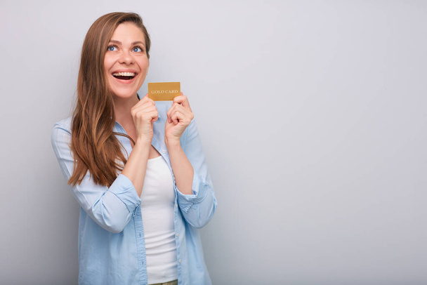 Credit card in hand of happy laughing woman with long hair dressed blue white shirt looking up isolated portrait   - Foto, imagen
