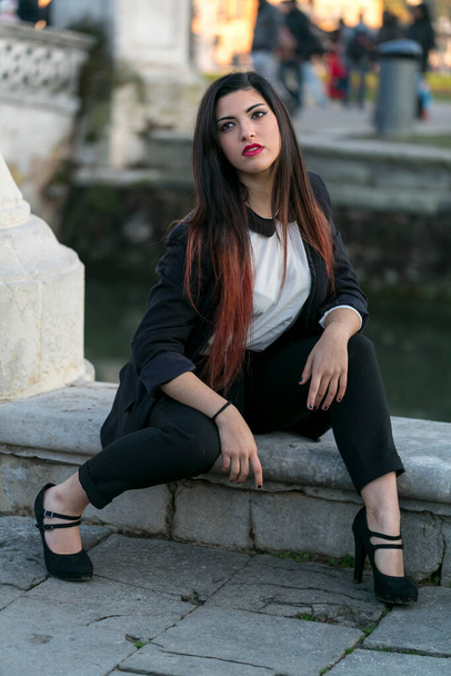 beautiful brunette girl sitting under marble column. High quality photo - Foto, afbeelding