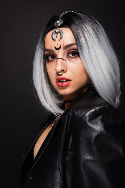 woman in witch halloween makeup and piercing looking at camera isolated on black - Foto, Bild