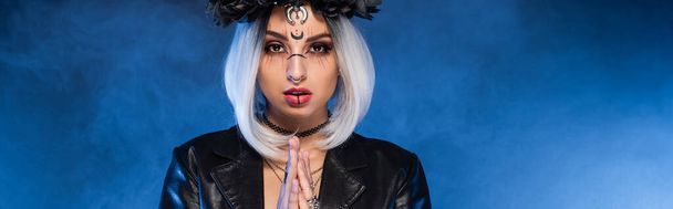 mladá žena v čarodějnice halloween make-up s modlícími se rukama na modrém mlhavém pozadí, prapor - Fotografie, Obrázek