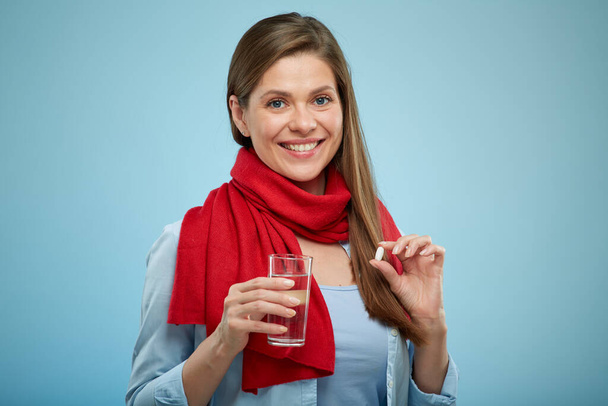 Smiling woman with drug pill water glass wearing red scarf. isolated female portrait. - 写真・画像