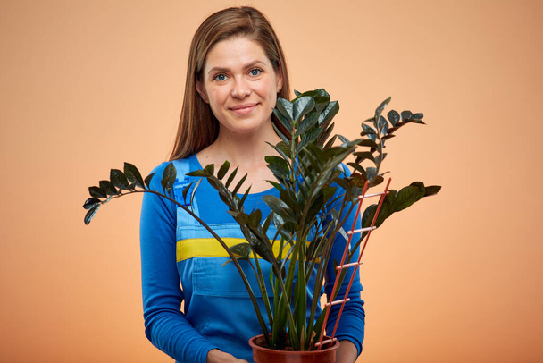 Woman in overalls holding houseplant. Isolated female portrait. - Foto, Imagem
