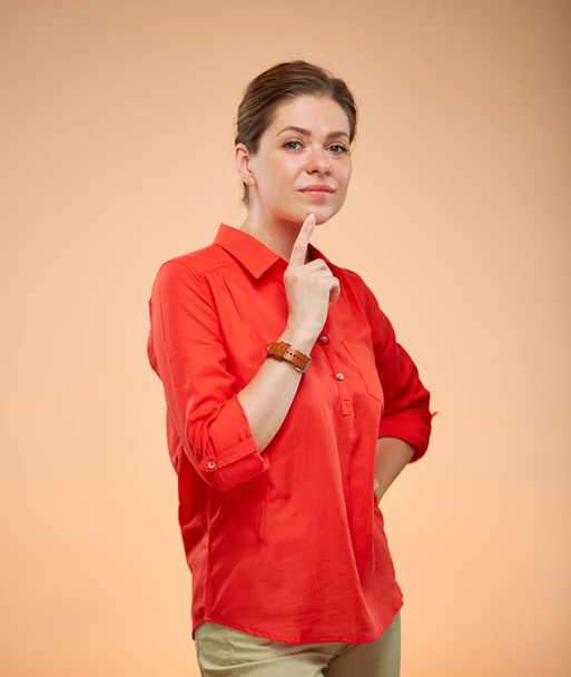 Serious young thinking lady in red shirt isolated portrait on beige background. - Fotografie, Obrázek