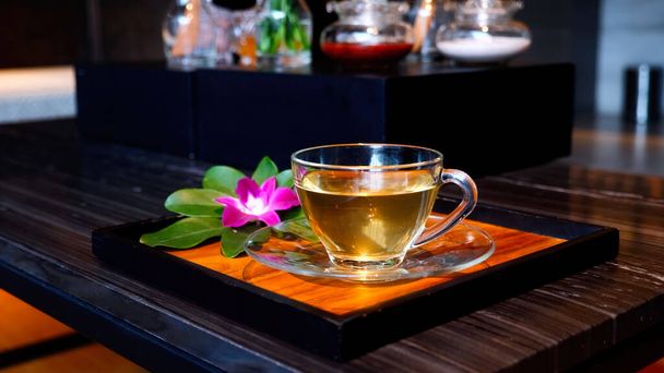 A cup of herbal ginger tea after relax massage at resort and spa salon. Healthy drinking water on tray with orchid flower in spa salon - Foto, immagini