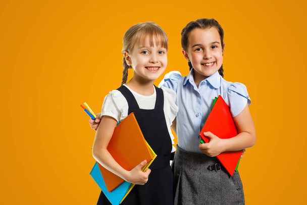 Little girls with books on orange background. - Foto, imagen