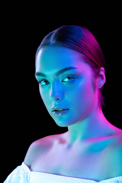 Perfection. Beauty portrait of young adorable woman with well-kept skin isolated over dark background in purple neon light. Concept of art, fashion, style, inspiration, emotions. Copy space for ad - Foto, immagini