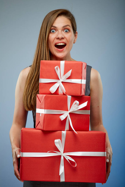 Amazed woman in business dress holding stack of red gift boxes. isolated female studio portrait. - Foto, Imagen