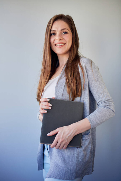 Smiling student or woman teacher wearing cassual holding book. Isolated portrait on gray. - Foto, imagen