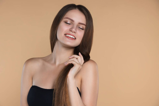 Young woman with strong healthy hair on beige background, space for text - Φωτογραφία, εικόνα