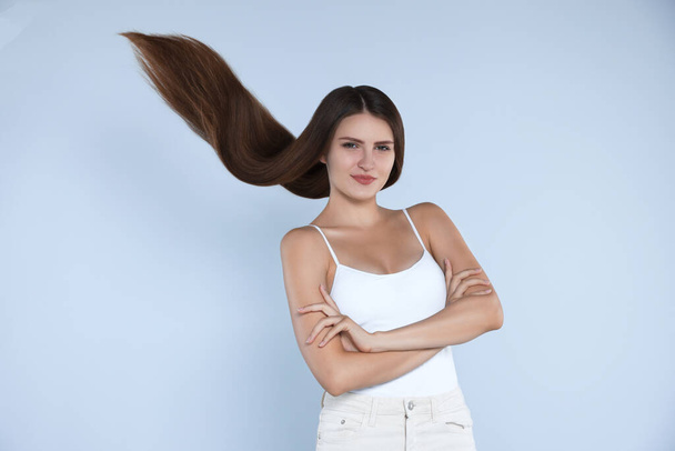 Young woman with strong healthy hair on light blue background - Foto, Imagem