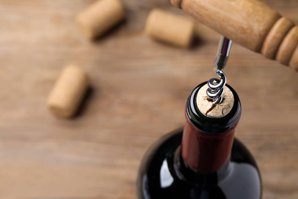 Opening wine bottle with corkscrew on table, closeup. Space for text - Photo, Image