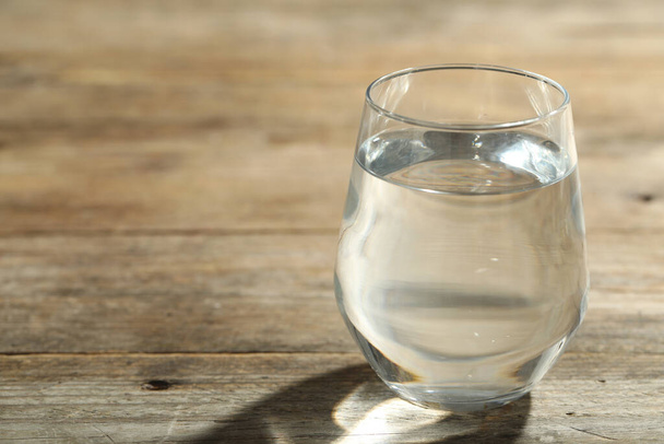 Glass of water on wooden table, closeup with space for text. Refreshing drink - Photo, image