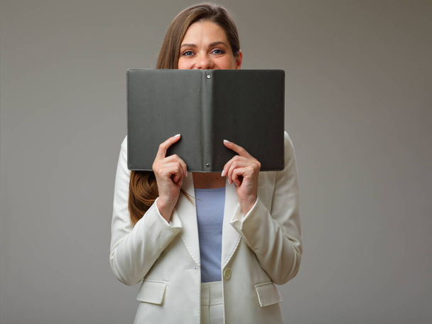 Young woman in white suit covered face with book, studio isolated portrait. - Foto, imagen