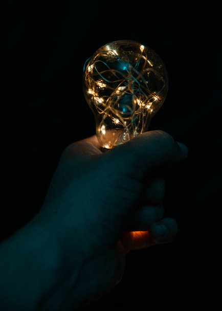 crystal glass with glowing light bulb on black background - Fotoğraf, Görsel