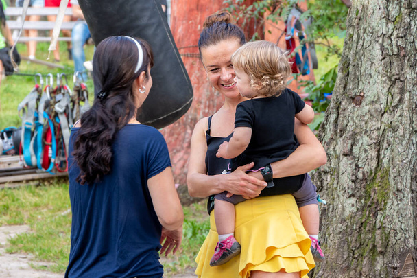 Une femme avec un enfant dans ses bras communique avec un ami dans la forêt. Concept : camp forestier touristique, sports et loisirs. - Photo, image