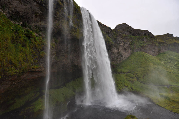 Seljalandsfoss es una cascada en Islandia. Seljalandsfoss se encuentra en la Región Sur de Islandia, justo por la Ruta 1. La cascada baja 60 m y es parte del río Seljalands que tiene su origen en el glaciar volcán Eyjafjallajokull. - Foto, imagen