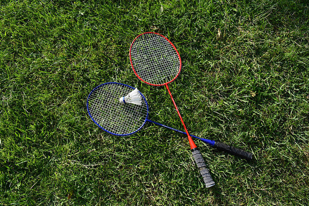 Badminton rackets and shuttlecock on the lawn. - Φωτογραφία, εικόνα