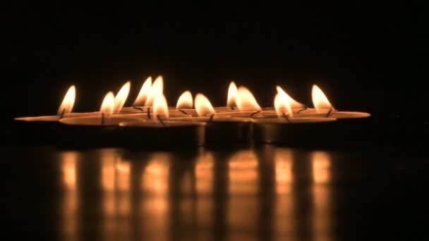 Very low angle view of Diwali diyas or candles. Deepawali lights at night. Dark background stock footage. - Felvétel, videó