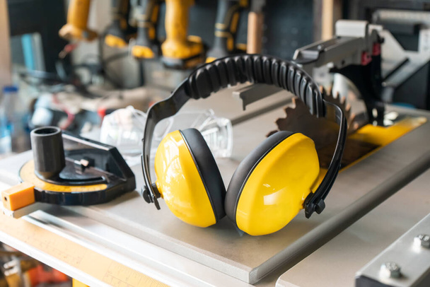 Earmuffs on Electric saw table in workshop .Woodwork safety concept . selective focus - Foto, imagen