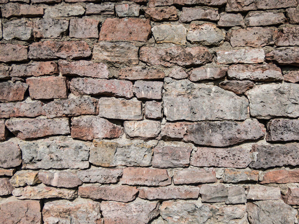 View of empty, old white, pink and grey brick wall background with copy space. A deteriorating old brick wall outdoors in bright sunlight - Foto, Imagen