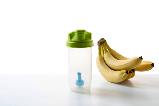 Shaker with measuring spoon and bananas. Sports flask and bananas. Diet and sports. Fitness and health. Front view. - Photo, Image