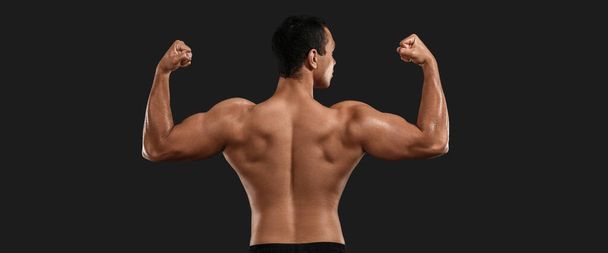 Sportlicher muskulöser Mann auf dunklem Hintergrund, Rückansicht - Foto, Bild