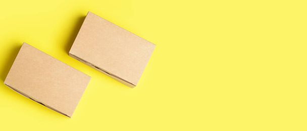 Пустые картонные коробки на желтом фоне с пробелами для текста, вид сверху - Фото, изображение