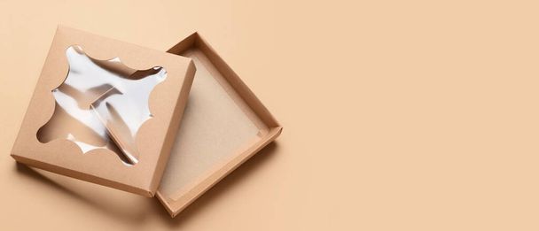 Caja de cartón abierta sobre fondo beige con espacio para texto - Foto, Imagen