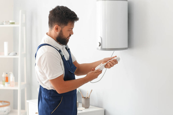 Male plumber with boiler's plug in bathroom - Фото, зображення