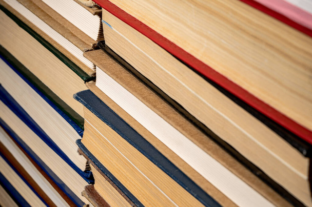Shelves with old books. Stacks of textbooks with red, blue, green covers and paper sheets in library. Stacked retro books in a bookstore. Side cut of books close up - Fotoğraf, Görsel