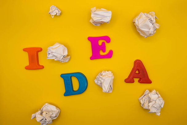 The word idea with colorful letters on yellow background top view - Фото, изображение
